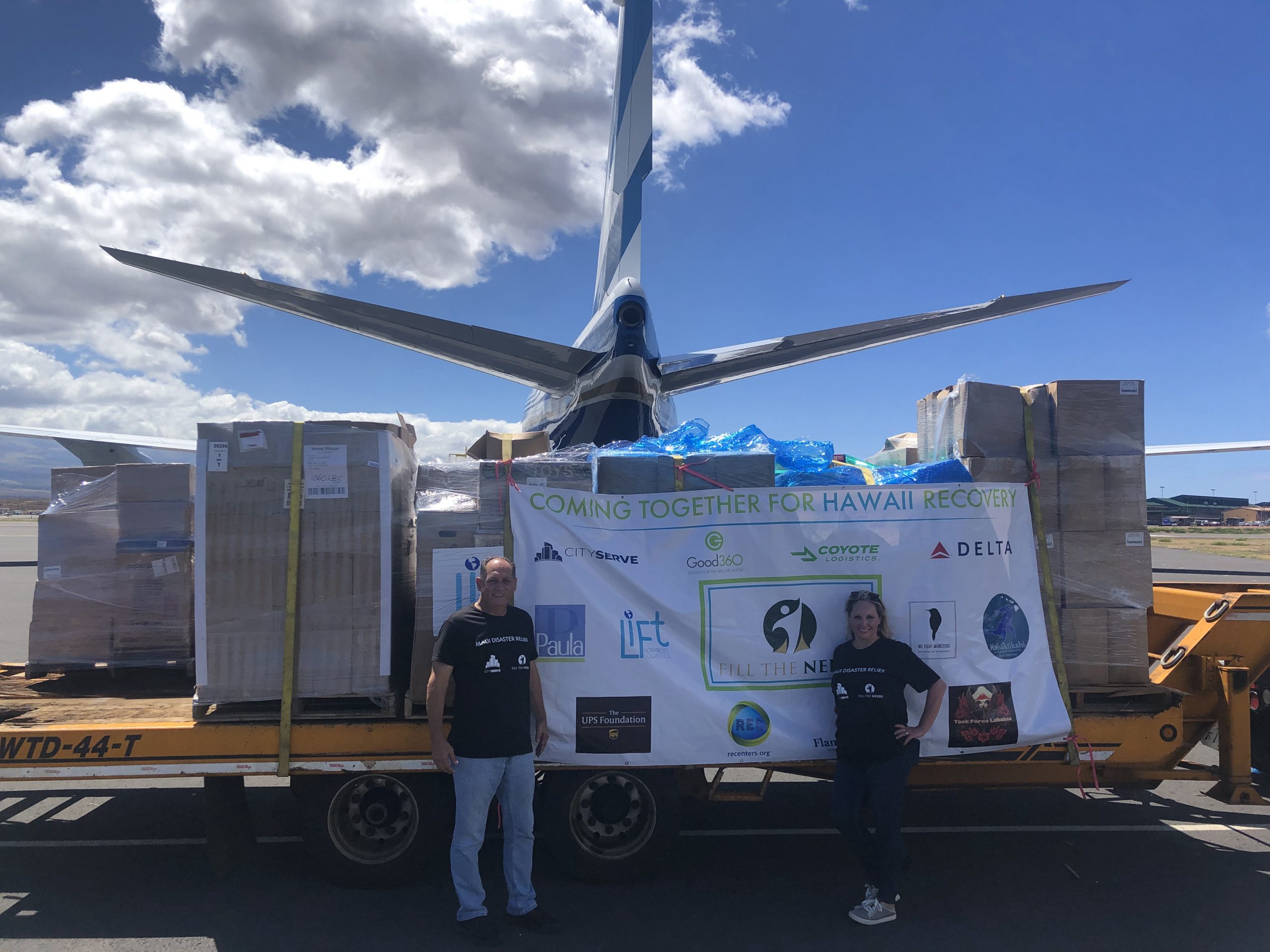 Volunteers stand in front of pallets of donated goods.