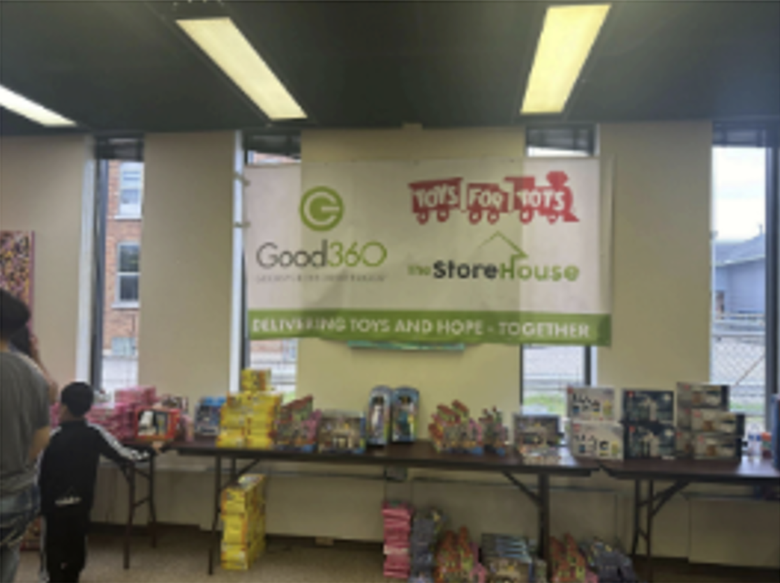 A Good360 and Toys for Tots co-branded banner hanging in front of donated toys.